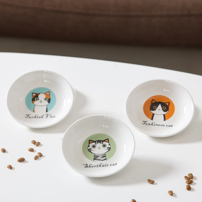 Three small round bowls with cat illustrations on a white surface.