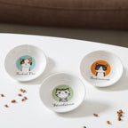 Three small round bowls with cat illustrations on a white surface.